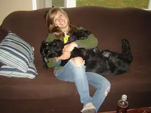 Smiling woman cuddling a black dog