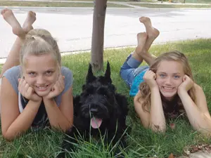 Two girls and a black dog outdoors