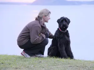 Woman with large black dog by lake