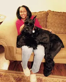Happy woman with large black dog indoors.